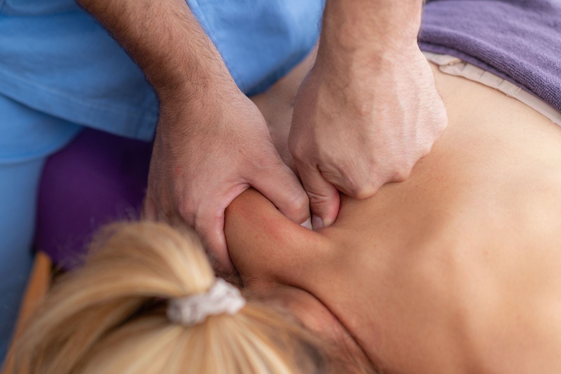 Hands applying pressure to a person’s upper back during a massage or therapy session