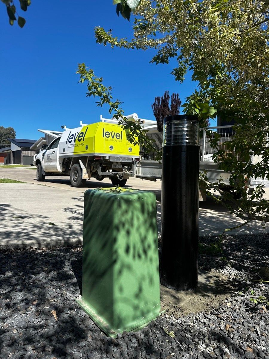 Yellow service truck parked on a sunny street beside green and black utility boxes  — Level Electrical & Air In Taminda, NSW
