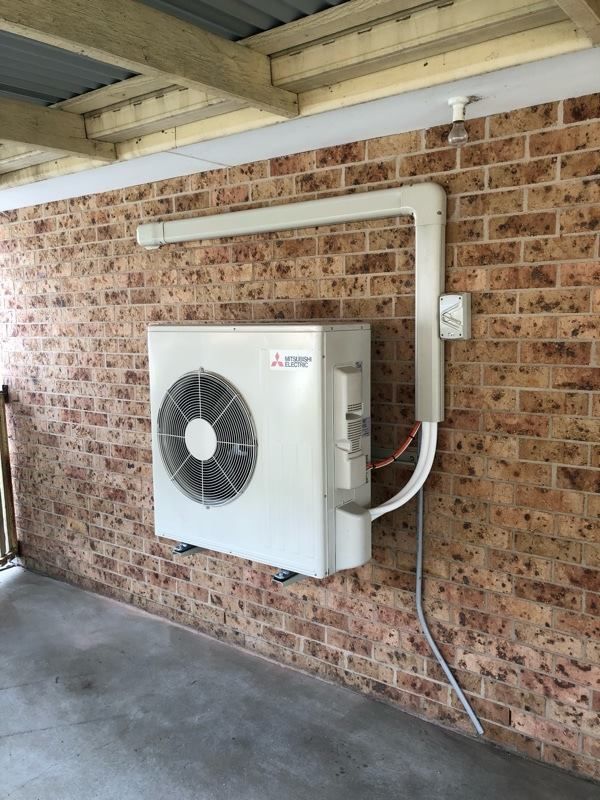 White Mitsubishi Air Conditioner Mounted on a Brick Wall With White Conduit — Level Electrical & Air In Taminda, NSW