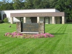 George's Funeral Chapel sign in front of a grassy lawn and pink flowers