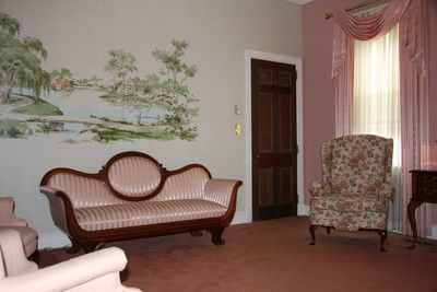 Elegant living room with floral wallpaper, pink drapes, and vintage sofa and armchair