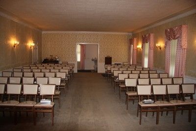 Empty conference room with rows of chairs, wall sconces, and draped windows