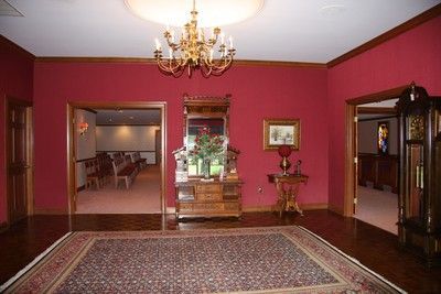 Elegant room with magenta walls, chandelier, patterned rug, and doorways to adjoining rooms