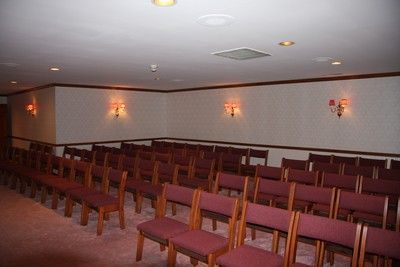 Empty conference room with rows of maroon chairs facing the front wall under soft ceiling lights