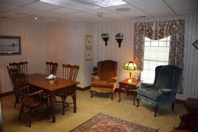 Cozy living room with wooden table, chairs, armchairs, lamp, window curtains, and wall art