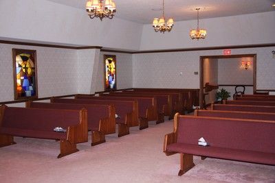 Empty church sanctuary with wooden pews, stained glass windows, and hanging lights