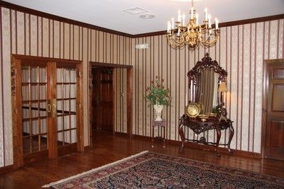 Elegant room with striped wallpaper, chandelier, ornate mirror, wooden doors, and patterned rug