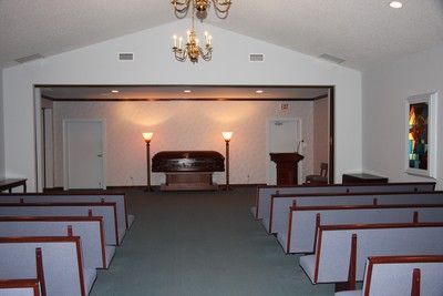 Empty church chapel with rows of pews facing a raised altar under warm lights