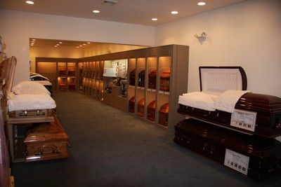 Mattress showroom with rows of beds and shelving under warm recessed lighting