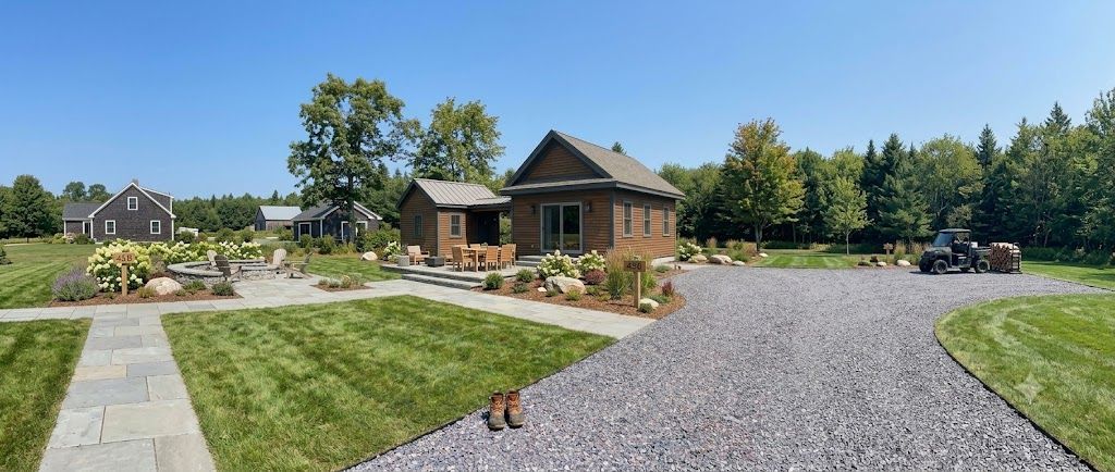 Modern farmhouse with landscaped yard, gravel driveway, and clear blue sky