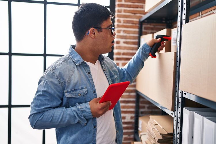 Man scanning boxes with a barcode reader in a storage area. Holds red tablet. Man scanning boxes with a barcode reader in a storage area. Holds red tablet.