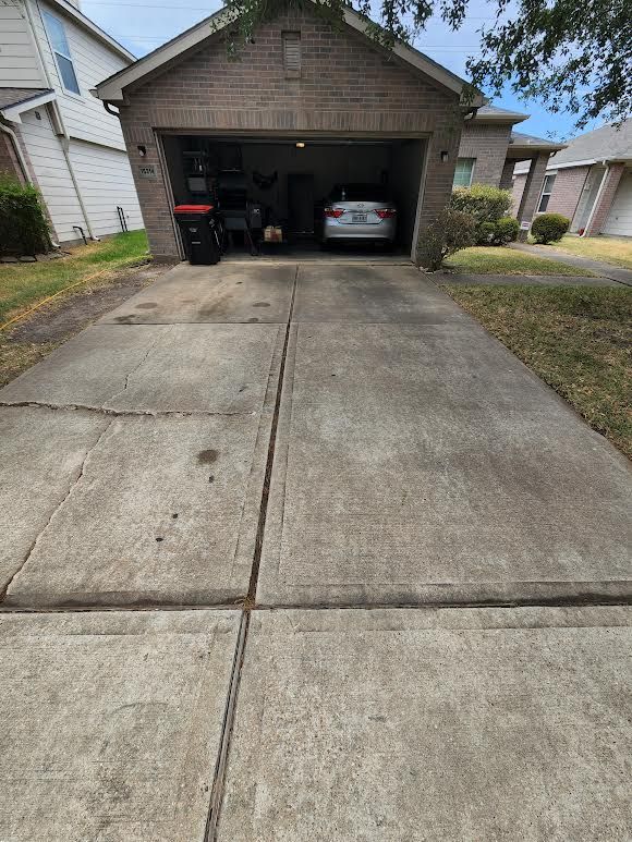 Concrete driveway leading to a brick two-car garage with two parked cars in a suburban home.