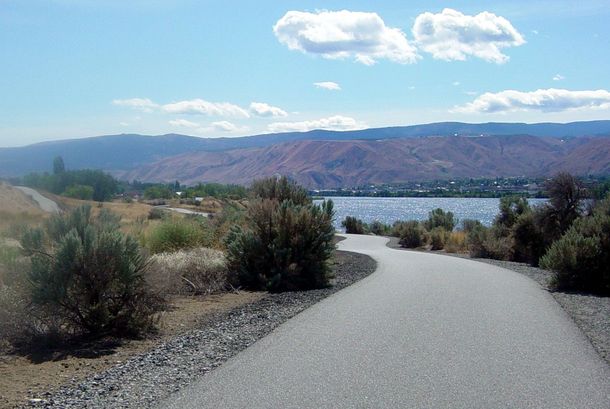 A road leading to a lake with mountains in the background