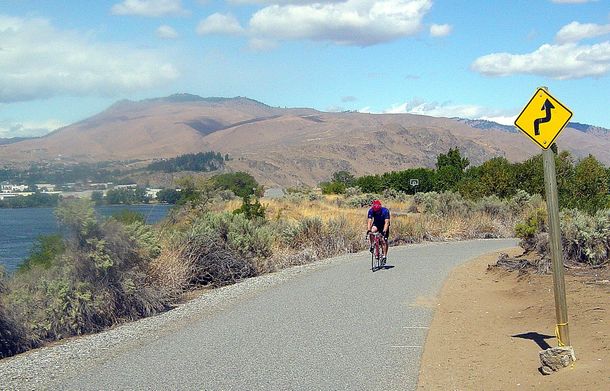 A person riding a bike down a road next to a sign