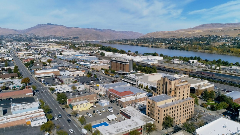 An aerial view of a city with a river and mountains in the background.
