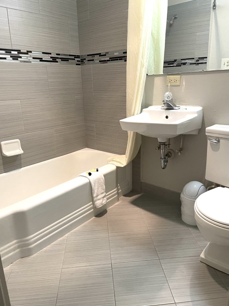 A bathroom with a sink , toilet , bathtub and mirror.