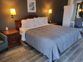 A hotel room with a king size bed and a chair.