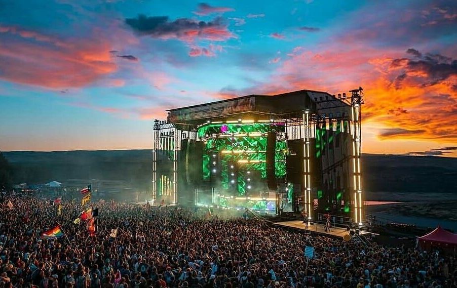 A large crowd of people are standing in front of a stage at a concert.