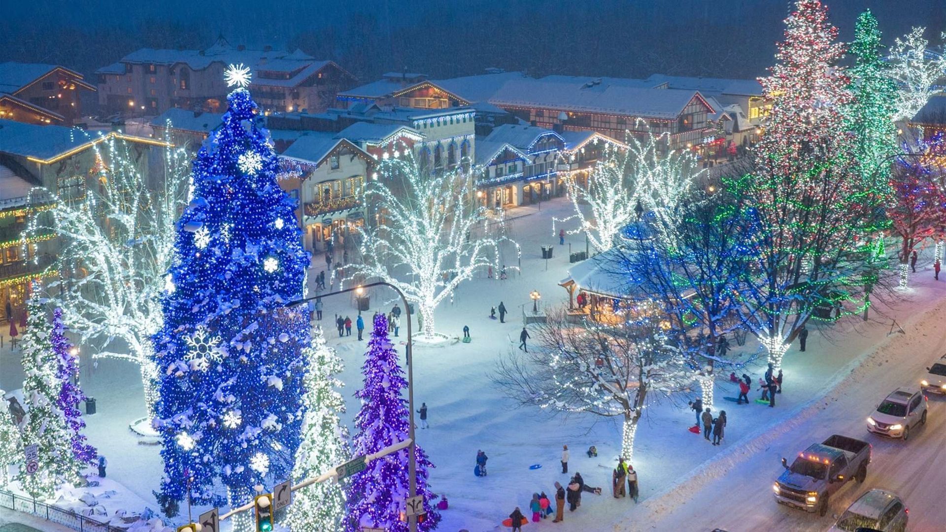 An aerial view of a city filled with christmas lights and trees.