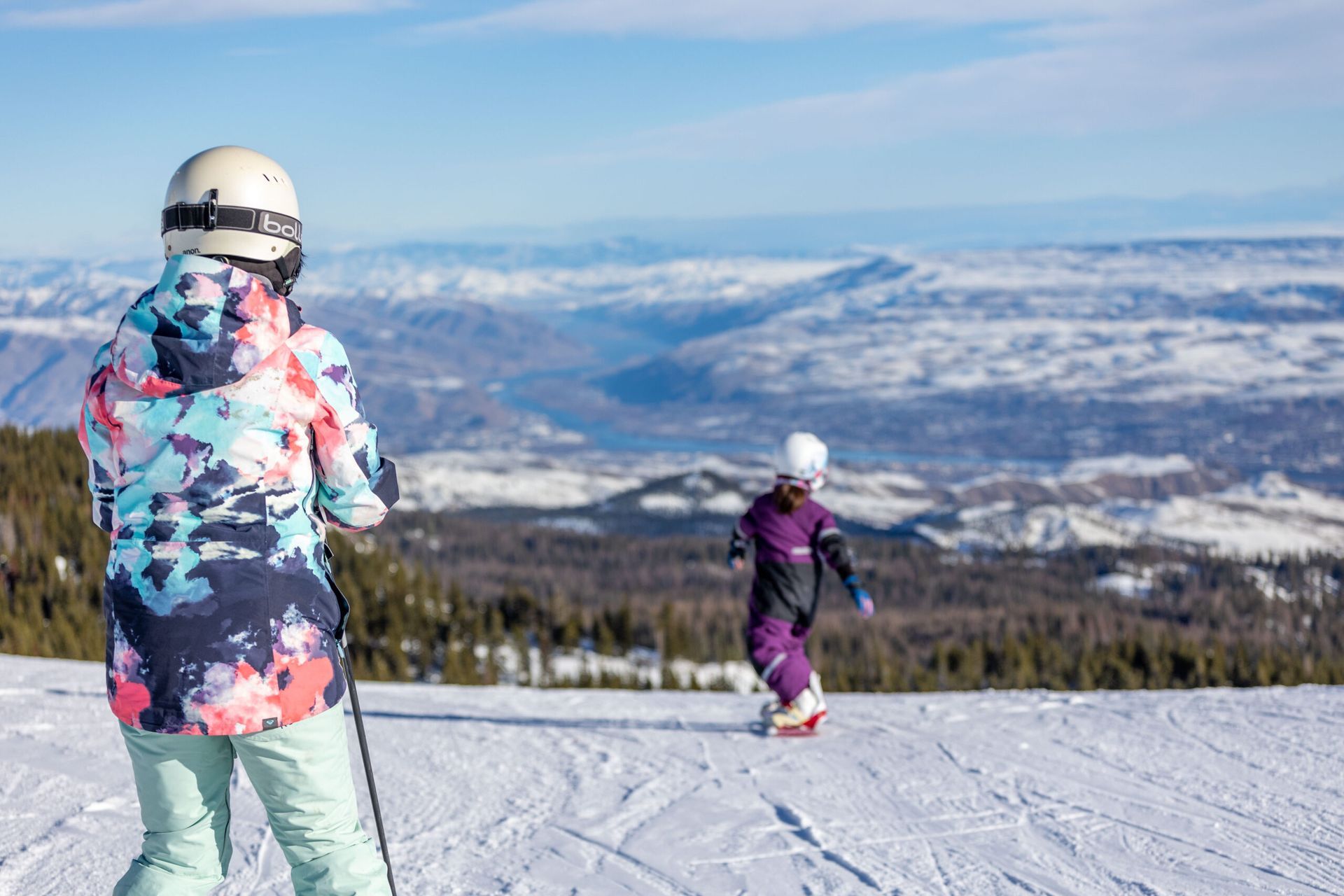 A woman and a child are skiing down a snow covered slope.