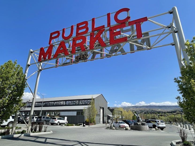 A sign for the public market hangs over a parking lot