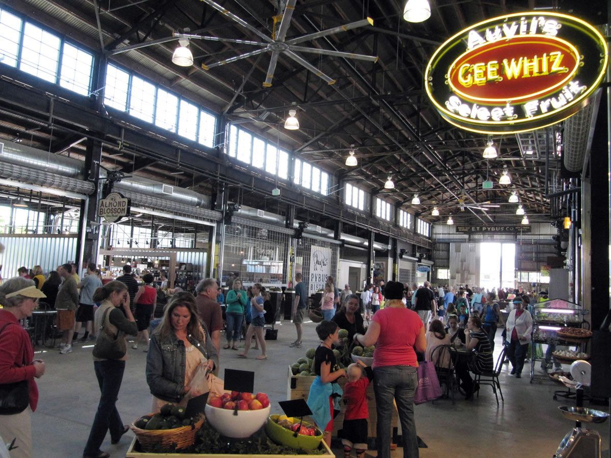 A crowd of people are gathered in a market with a sign that says gree whiz