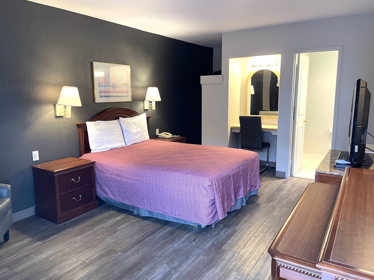 A hotel room with a king size bed and a flat screen tv.