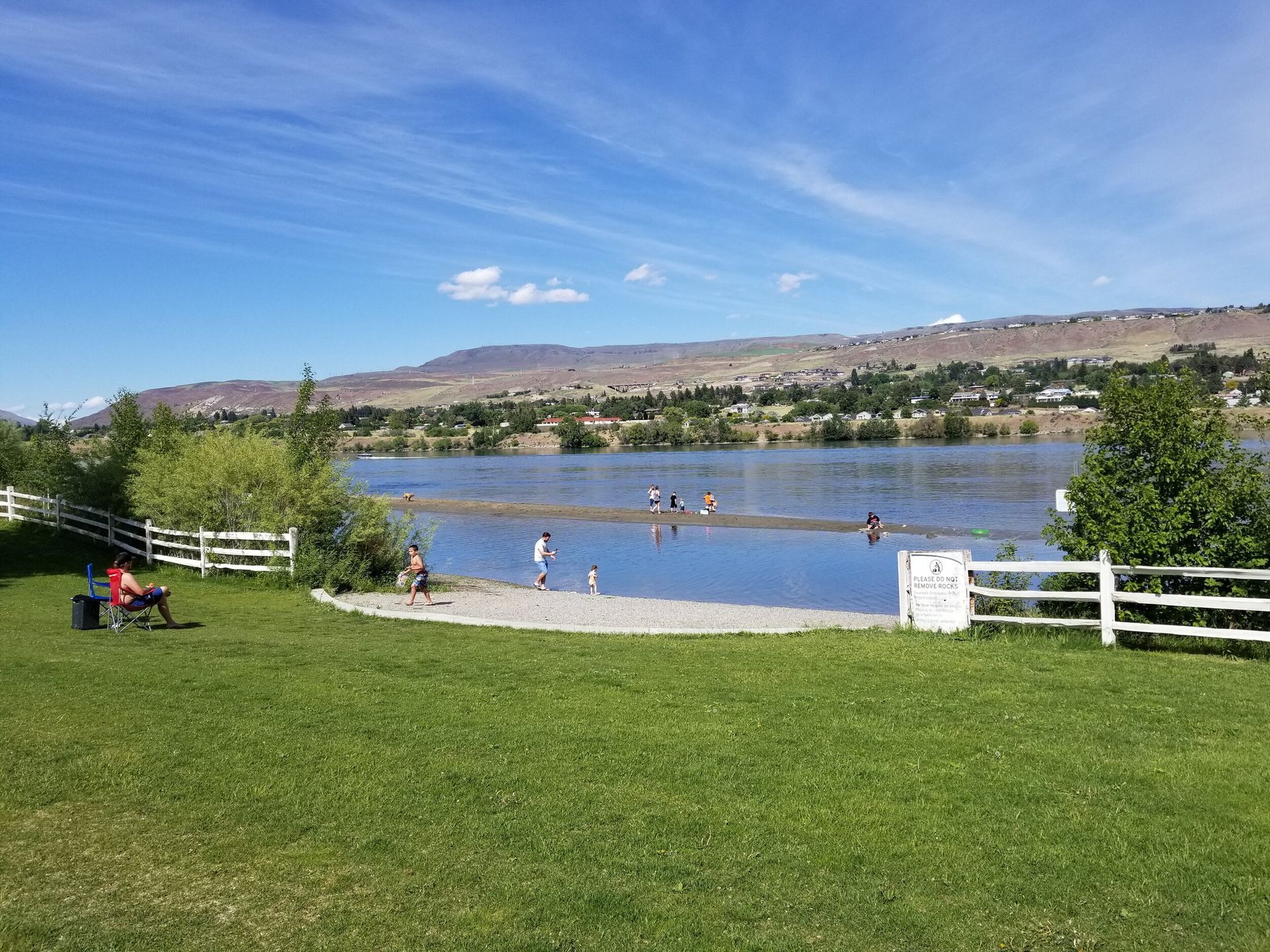 A person is sitting on a bench in front of a lake.