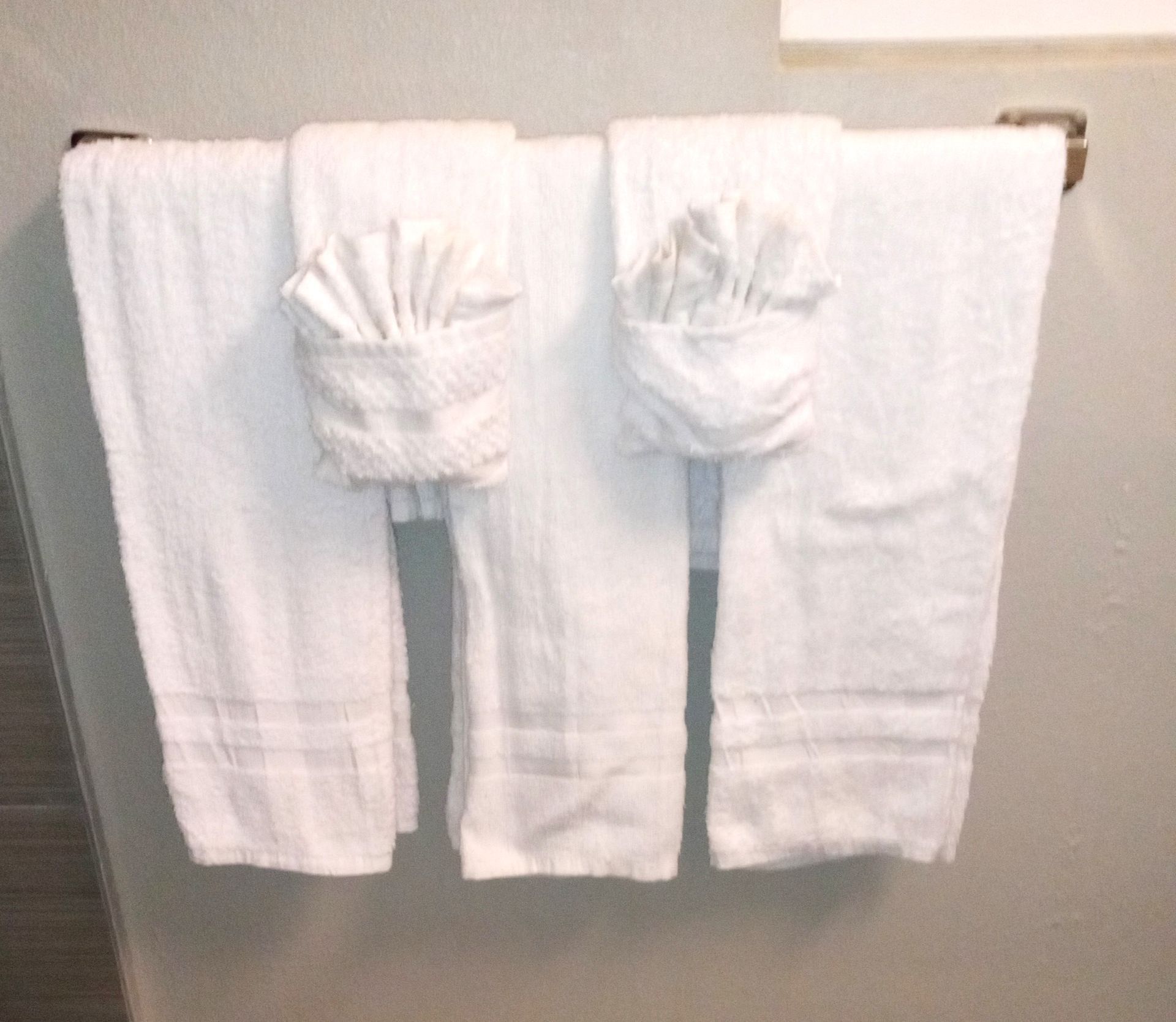 Three white towels are hanging on a towel rack