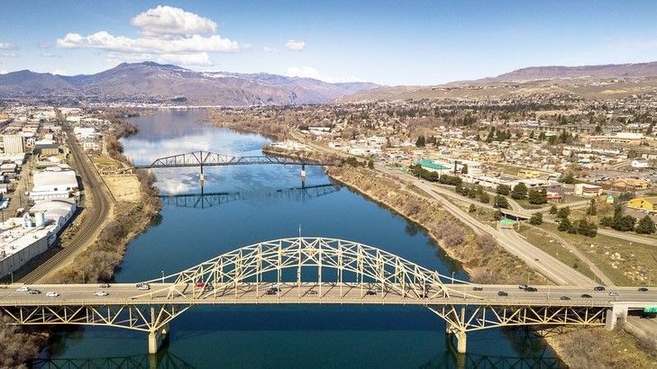 An aerial view of a bridge over a river with mountains in the background.