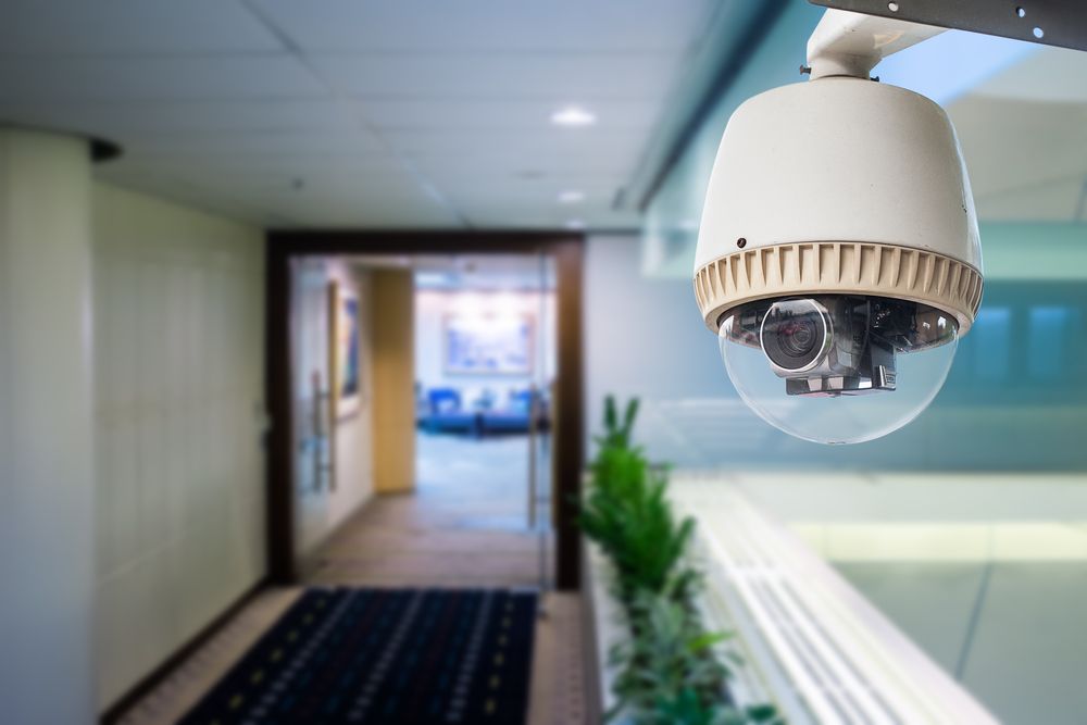 Security camera mounted in a modern office hallway, overlooking a doorway and interior space — Jendata In Garbutt, QLD