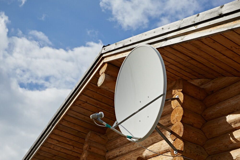 A Satellite Dish is Mounted on the Roof of a Log Cabin — Jendata In Garbutt, QLD