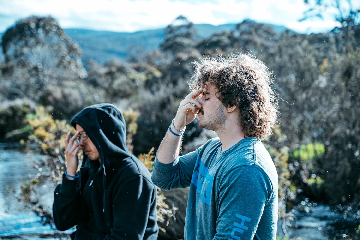 A man is sitting on a yoga mat in a room.