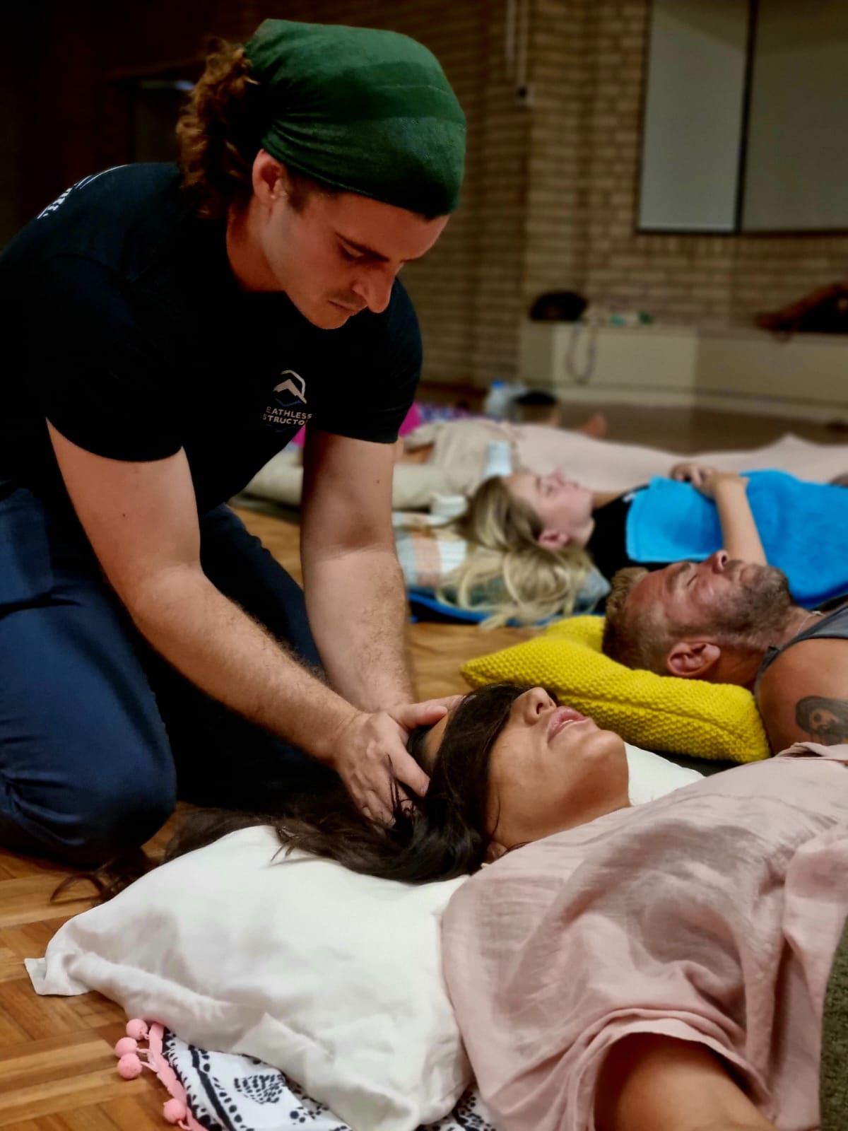 A man is kneeling down next to a woman laying on the floor.