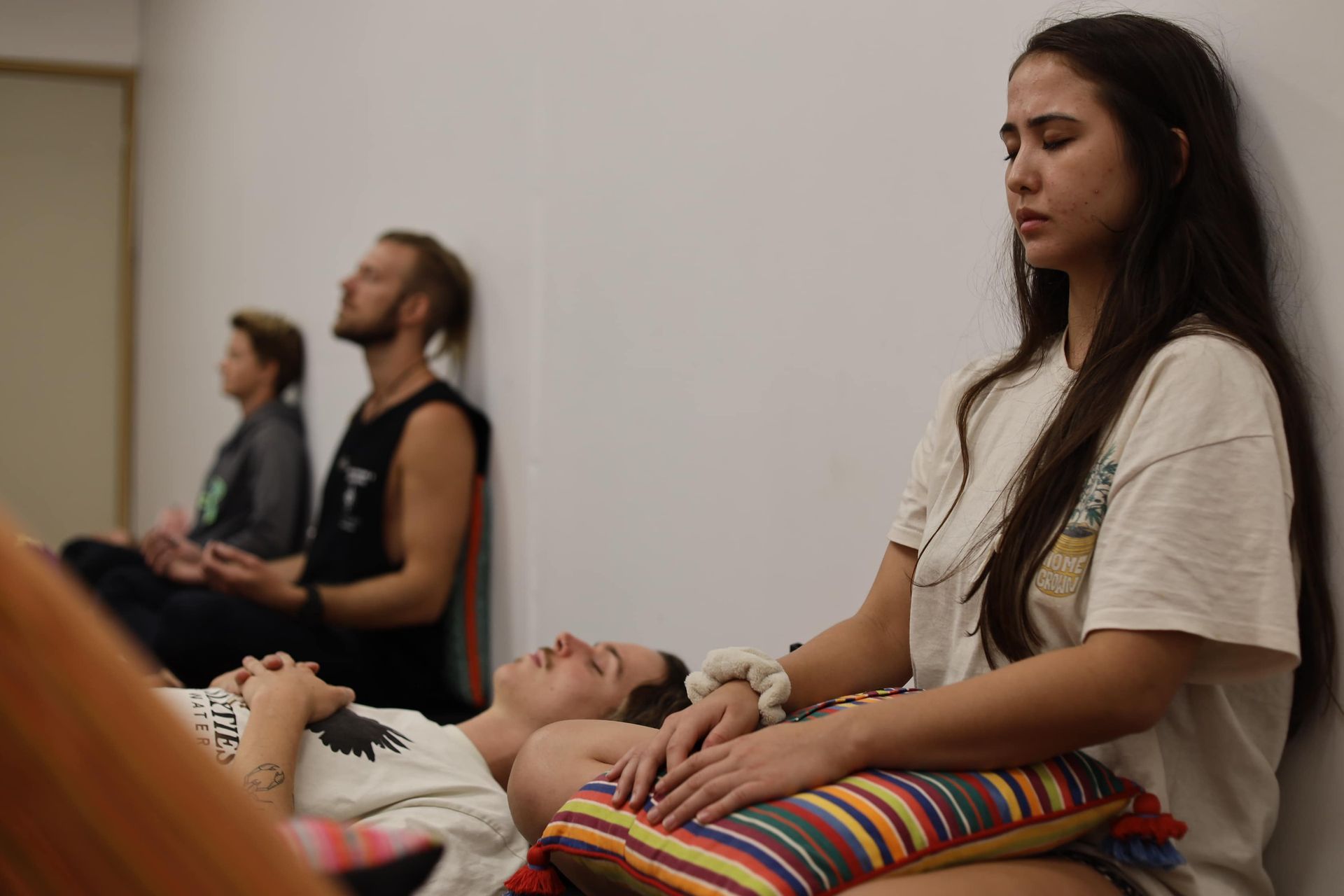 A group of people are sitting in a room with their eyes closed.