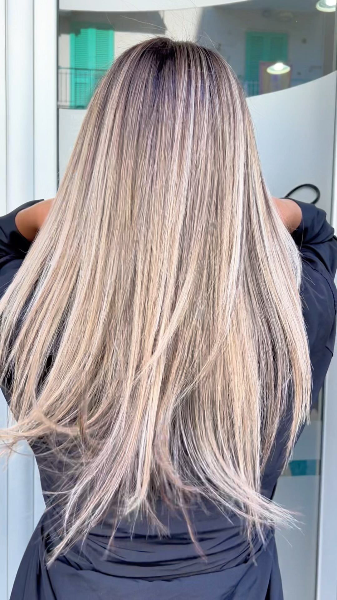 Una donna con lunghi capelli biondi è in piedi davanti a uno specchio.
