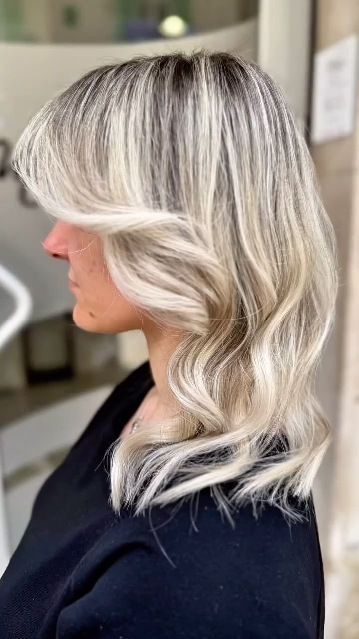 Una donna con i capelli biondi e una camicia nera è seduta su una sedia.