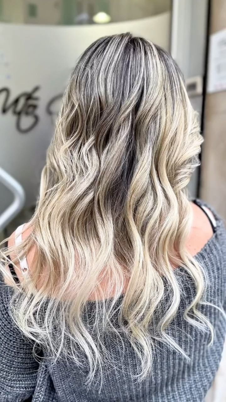 Una donna con lunghi capelli biondi indossa un maglione grigio.
