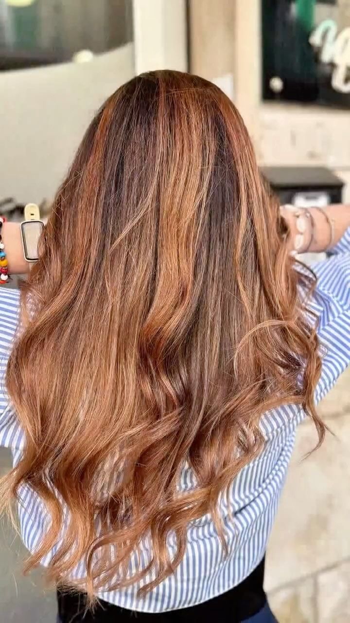 Una donna con lunghi capelli castani indossa una camicia a righe blu e bianche.