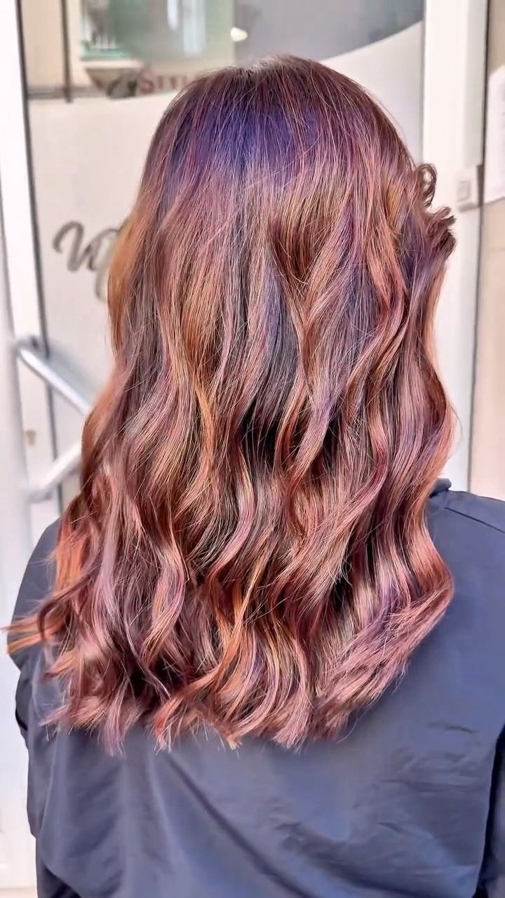 Una donna con lunghi capelli castani ondulati è in piedi davanti a una porta.