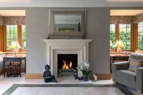 Modern minimalist fireplace with a white tiled surround, featuring a small fire burning inside, adding warmth to a cozy living space.