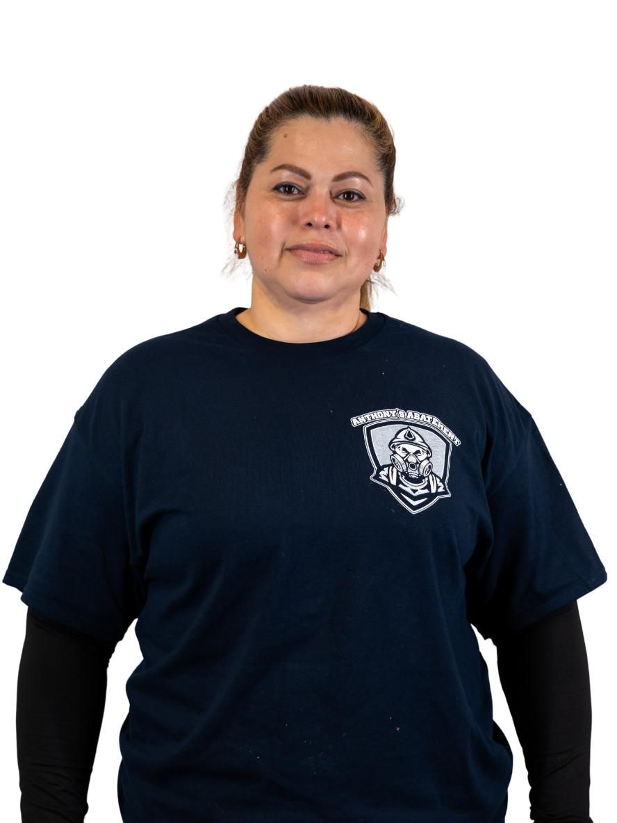 Woman standing against a white background wearing a navy T-shirt over a black long-sleeve shirt