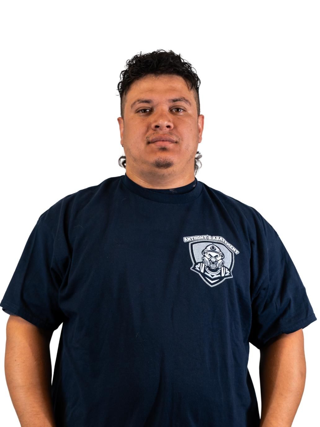 Man in navy T-shirt with a white emblem, standing against a plain white background.