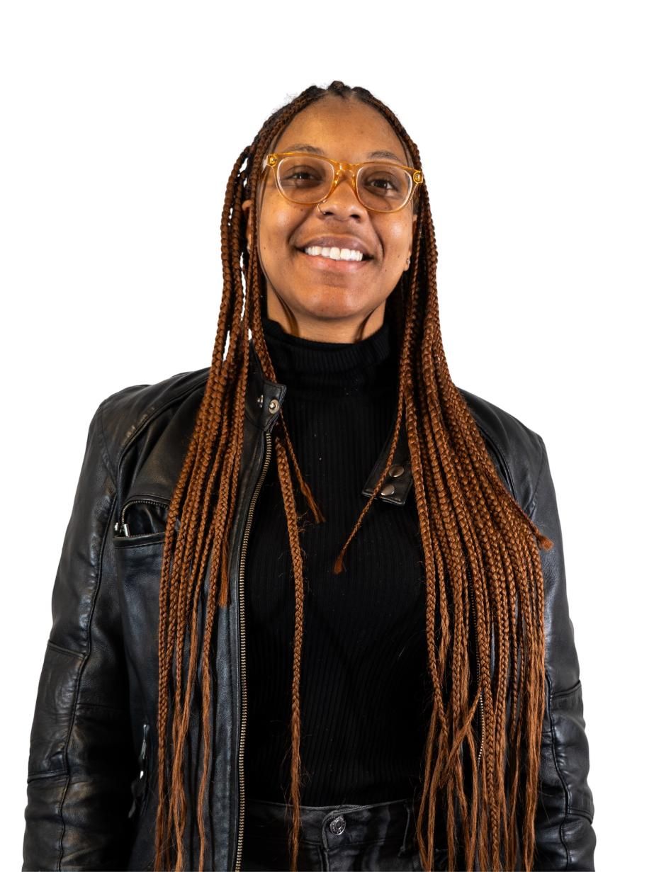 Smiling person with long braids, glasses, black turtleneck, and leather jacket against a white background