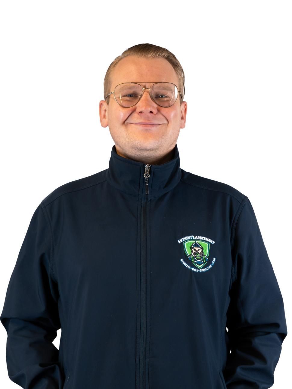 Man in a navy zip-up jacket with a small logo, standing against a white background.