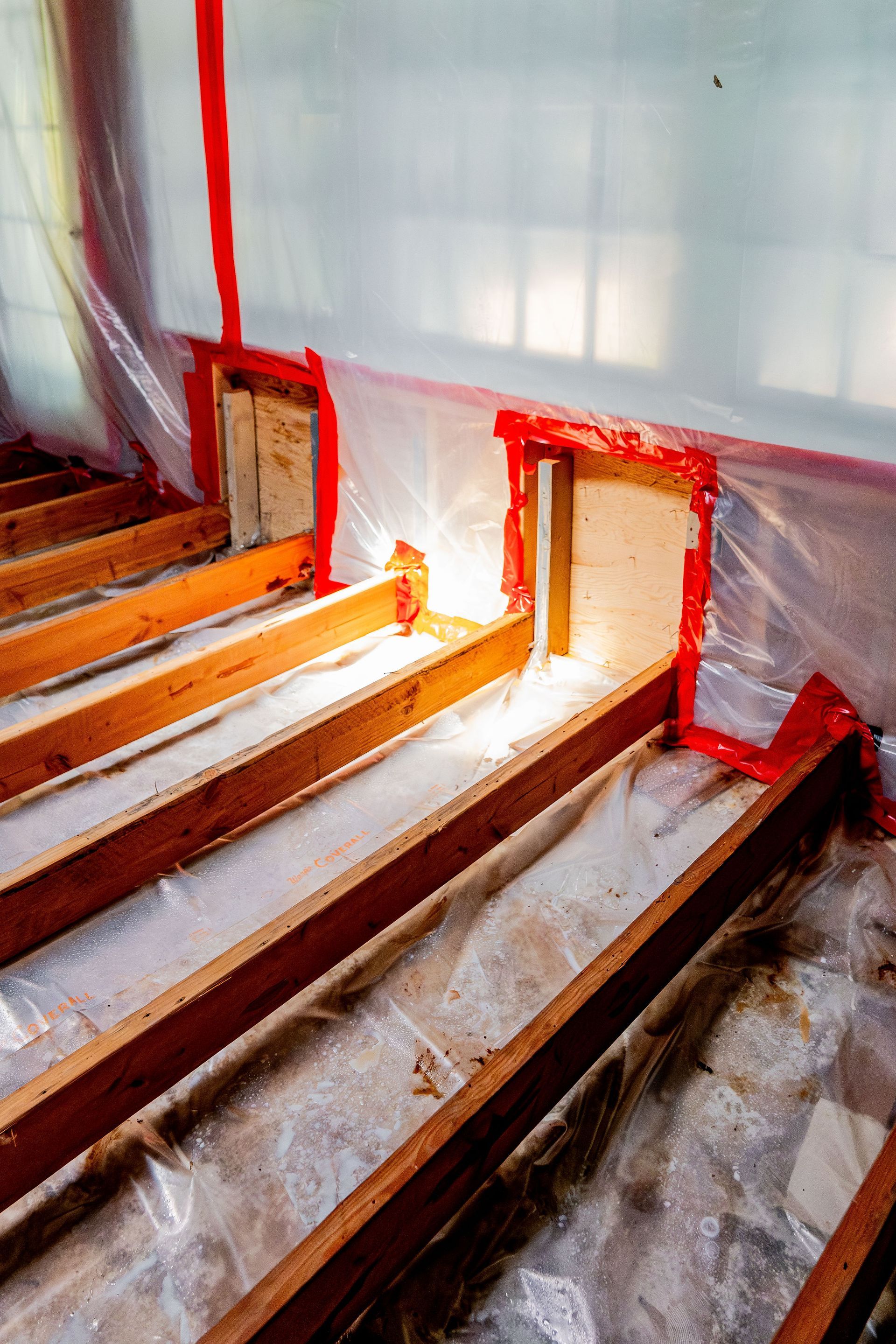 Basement stairwell under construction with wooden steps, red tape, and insulation along the walls