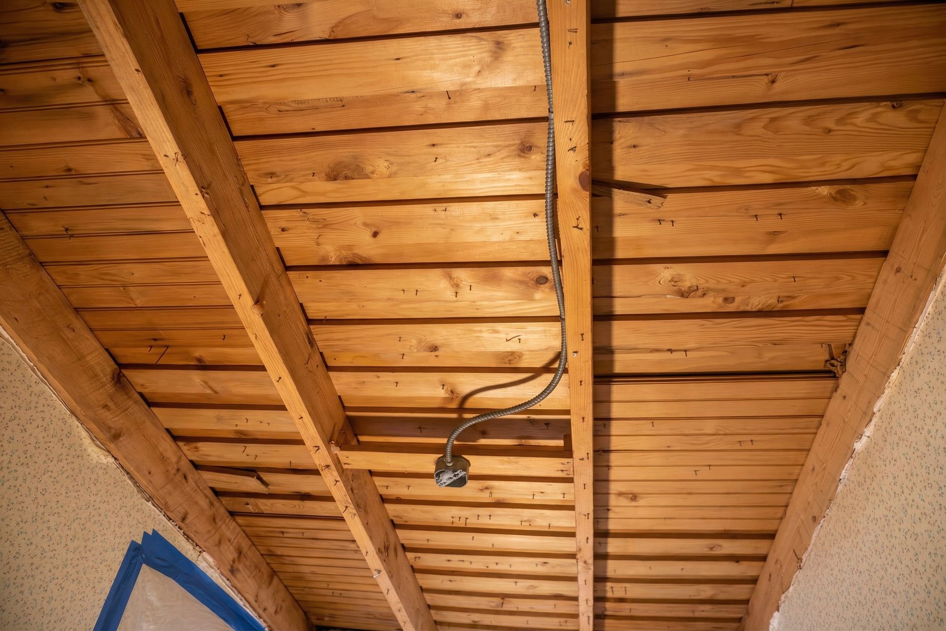 Wooden ceiling with exposed beams and a hanging light fixture over a hallway