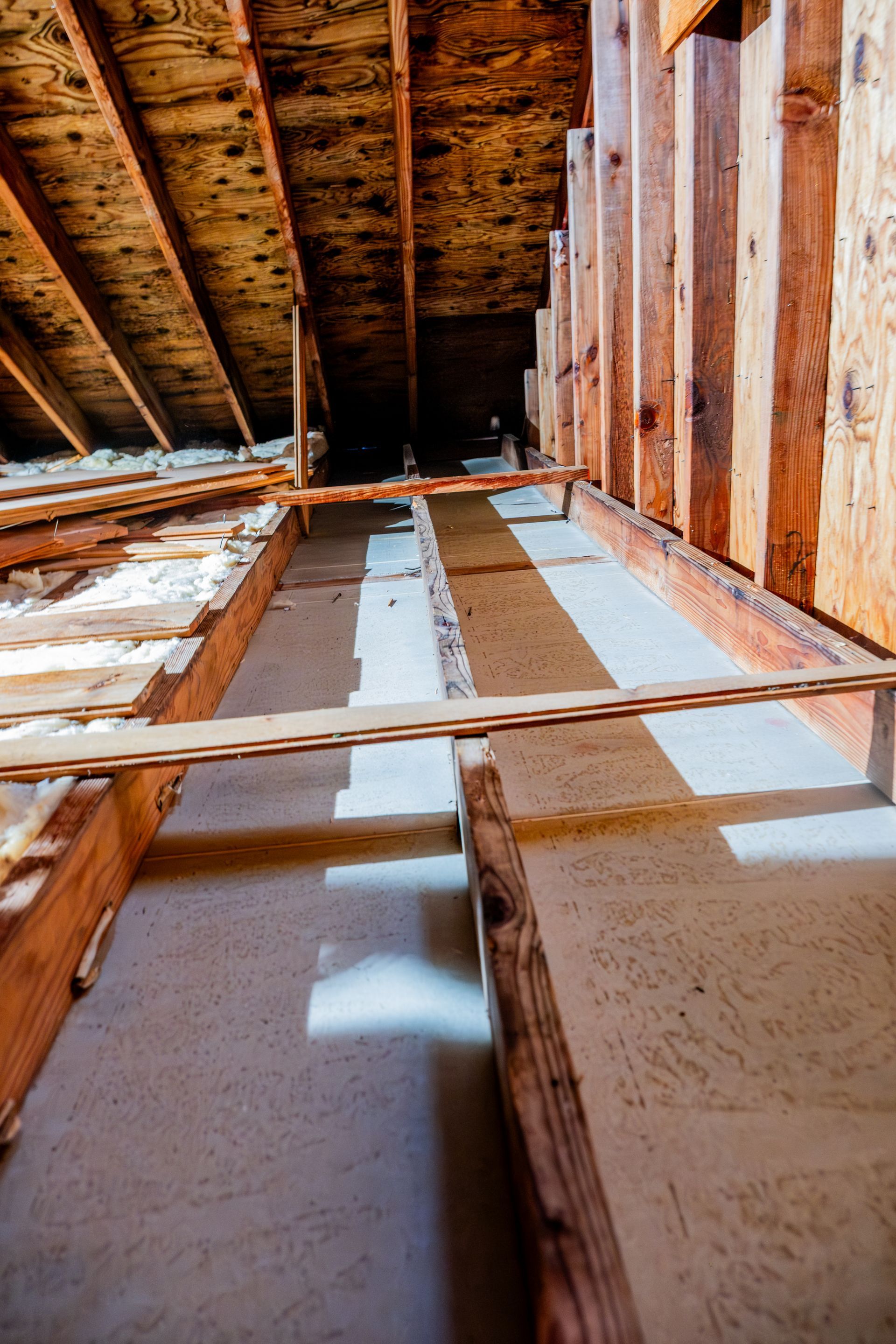 Interior attic framing with exposed wooden beams and unfinished walls, viewed upward through a narrow opening