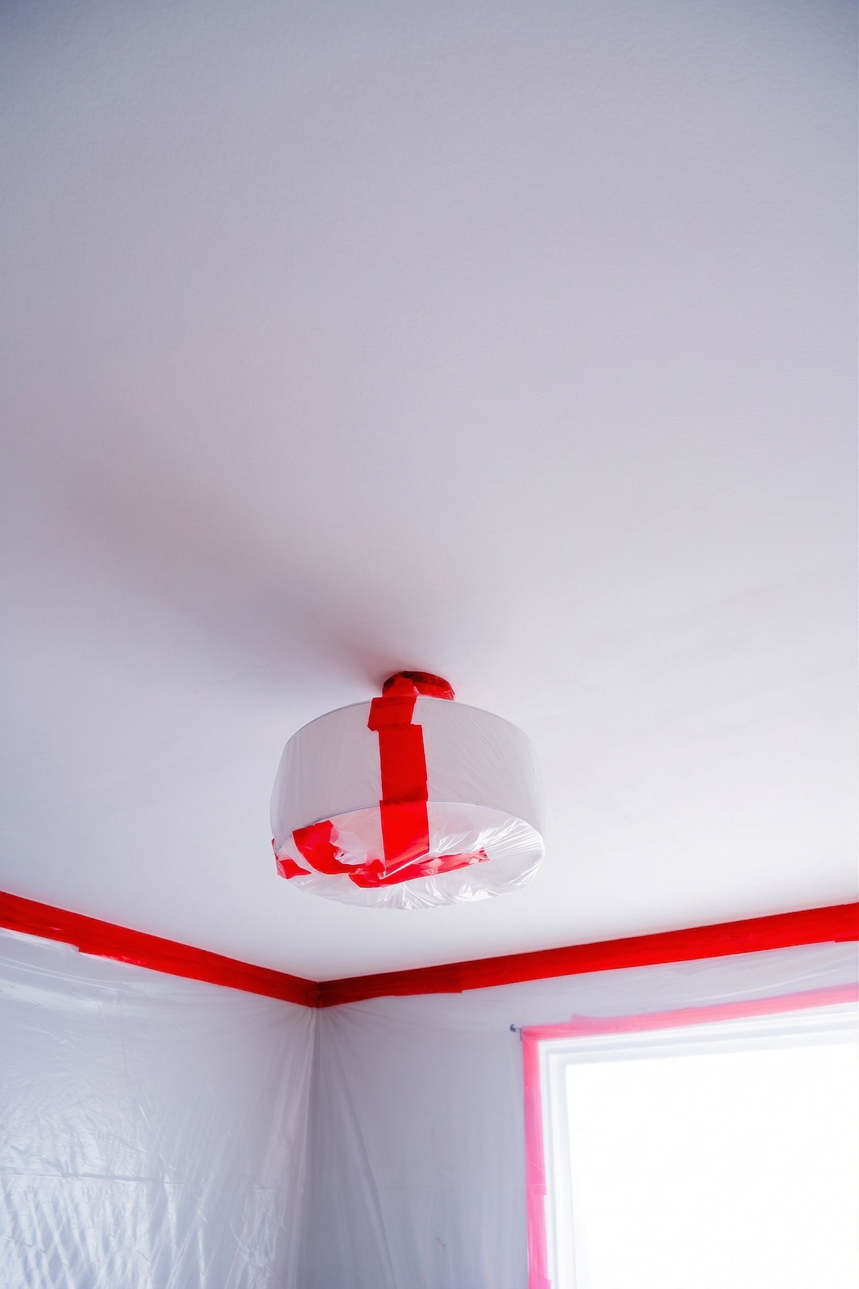 White ceiling with a red-and-white hanging light fixture in a room with red trim and a window