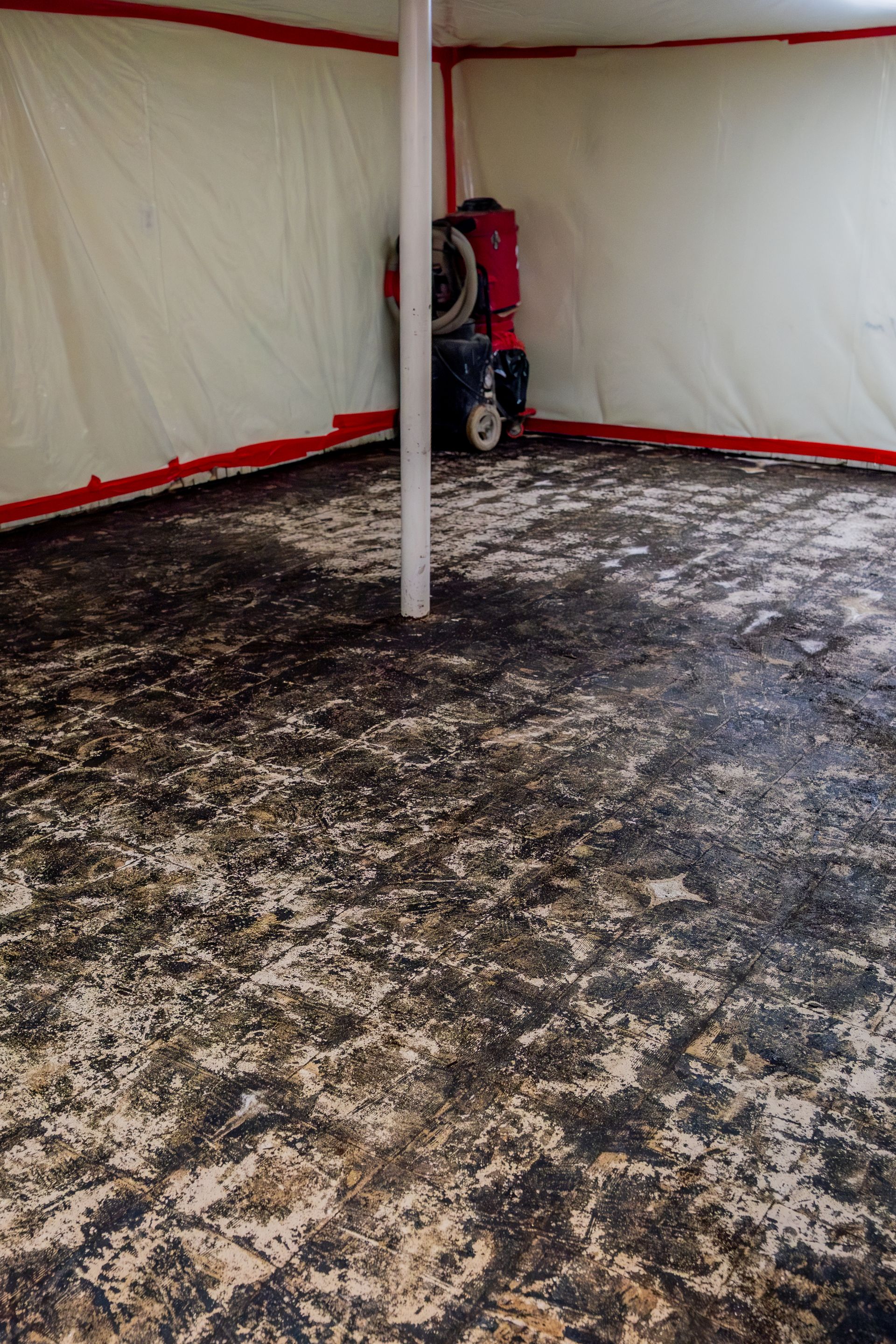 Indoor tent with white walls, red trim, and a dirt-covered floor, centered around a support pole.
